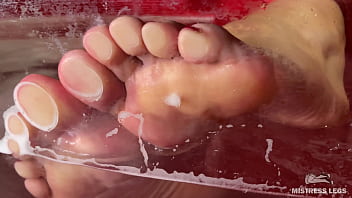 Mistress&#039_s wet wrinkled soles are pressed against the glass in the bathtub